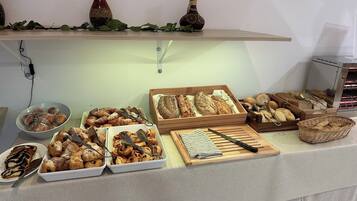 A buffet with various baked goods and pastries, including bread, croissants, and rolls.