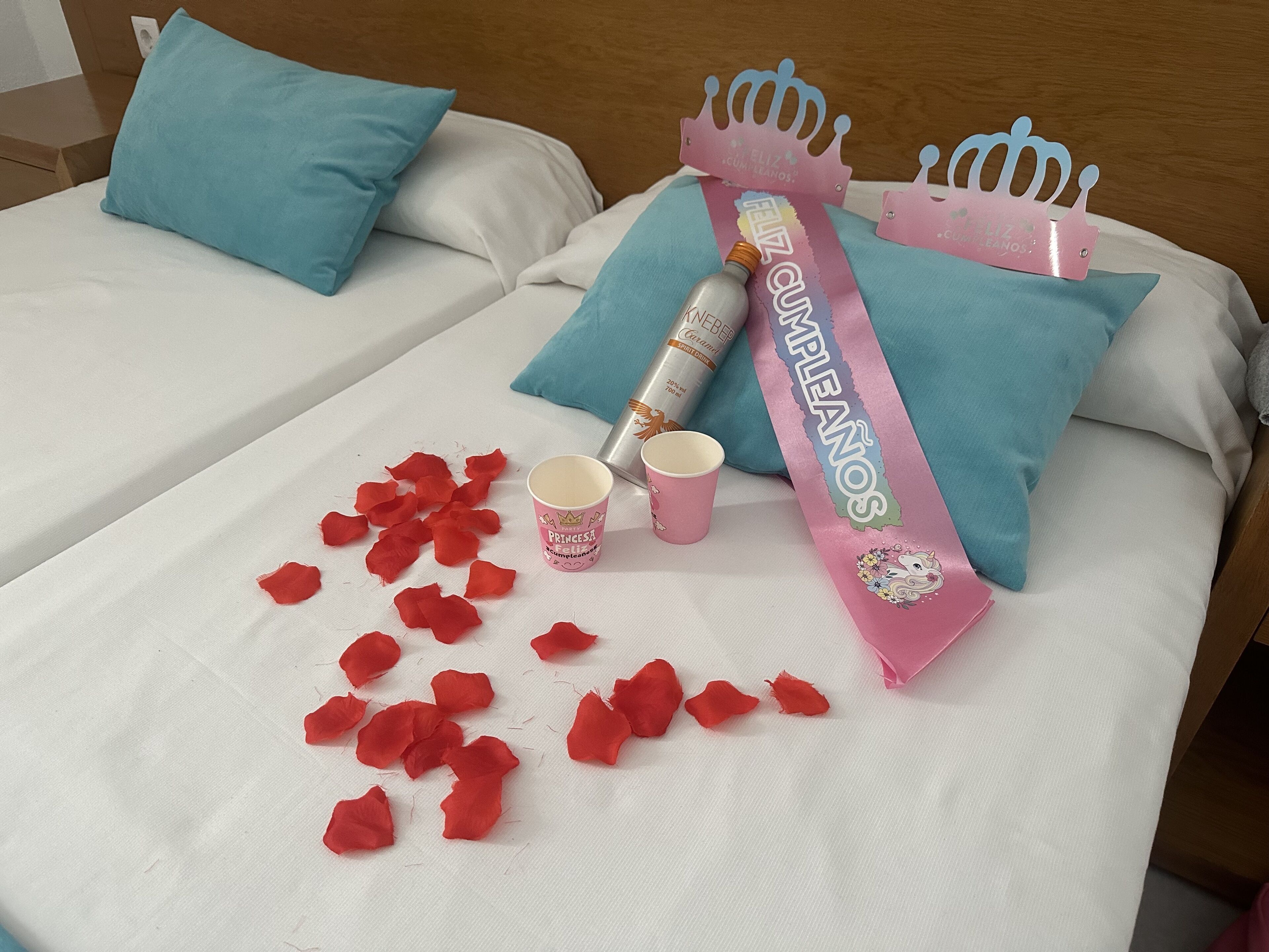 Una cama con un cartel rosa, una botella y una taza encima.