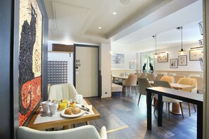 A modern dining area with a table set for breakfast, including croissants and juice. There are multiple dining tables and chairs, and the room has a contemporary design with artwork on the walls. - Hôtel Le Chat Noir (Paris)