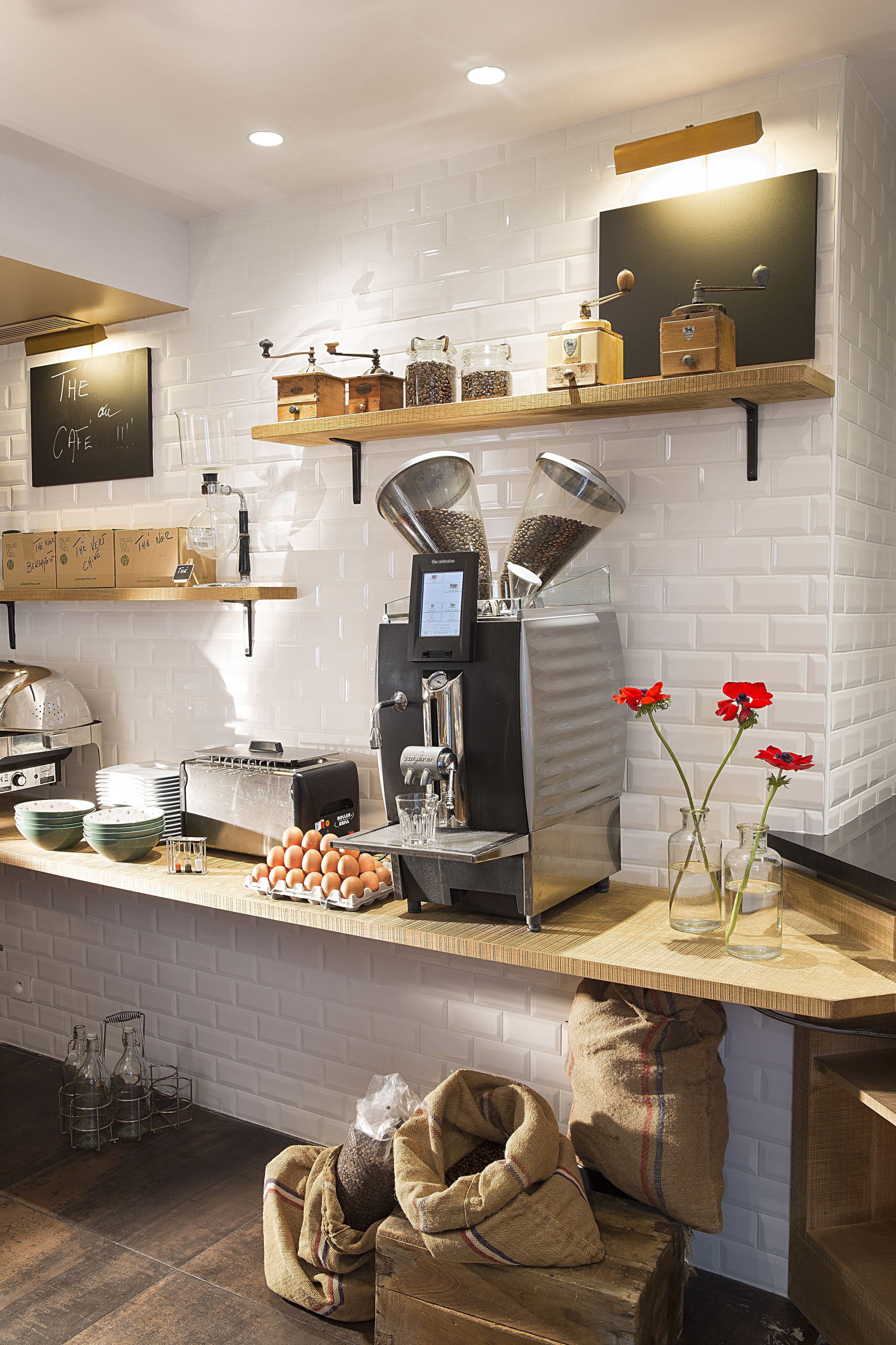 A modern kitchen with a coffee machine, shelves with jars, and a chalkboard sign.