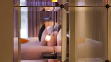 Un intérieur moderne avec une cloison en verre aux motifs géométriques et un coin salon confortable agrémenté de coussins et d’une lampe.