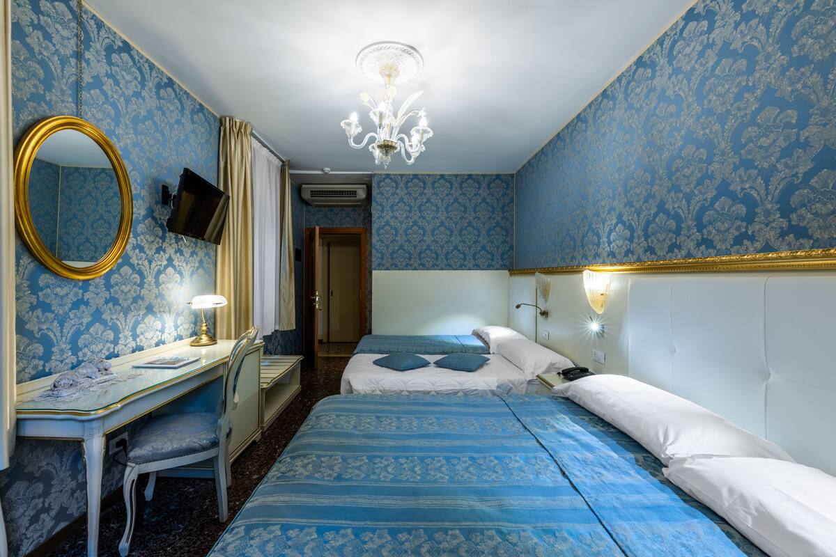 Une chambre avec deux lits, un bureau avec une chaise, un miroir et un lustre.