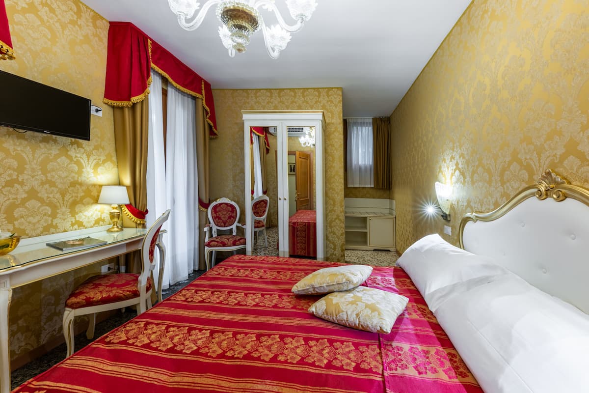 Une chambre d’hôtel équipée d’un lit, d’un bureau, d’une chaise, d’une télévision et d’une armoire.