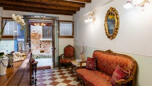 A room with a checkered floor, a wooden ceiling, a sofa, a chair, a table, and a mirror.