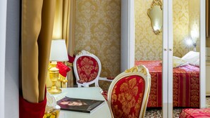 A hotel room with a bed, a chair, a table with a lamp, and a mirror.