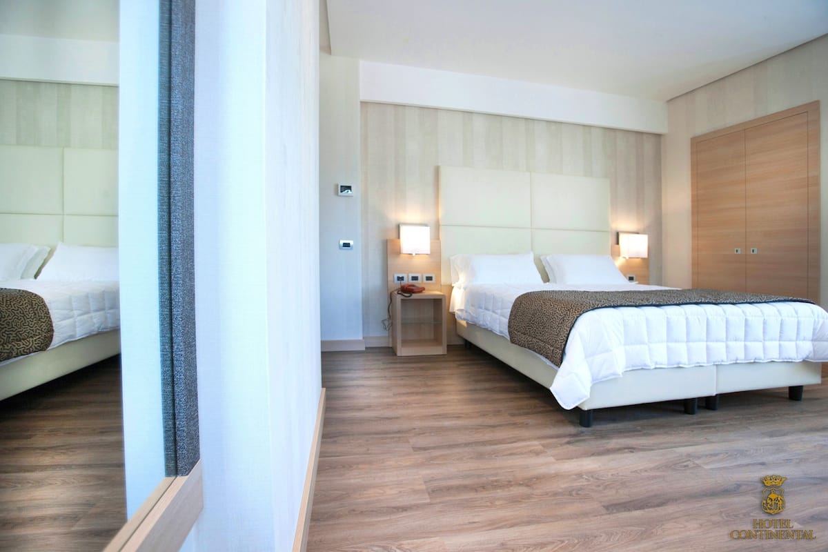 Habitación de hotel con dos camas, piso de madera y un amplio armario.