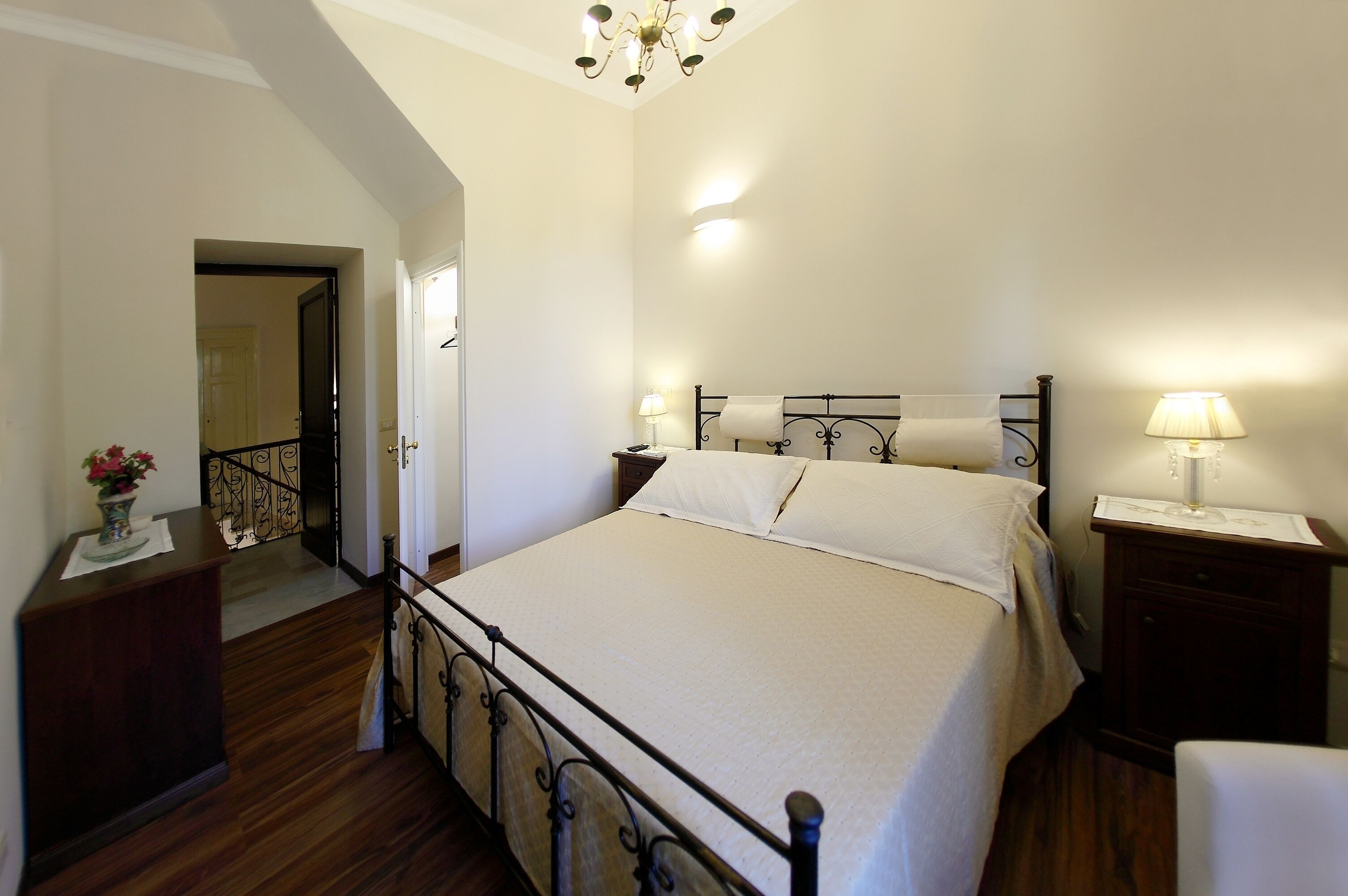 Une chambre à coucher avec un grand lit, des tables de chevet, une commode, un miroir et un lustre.