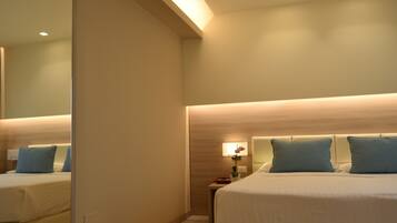 Una habitación de hotel con dos camas, una mesita de noche, una lámpara y un espejo.