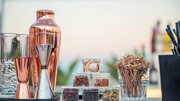 Verschiedene Gläser und Behälter, darunter eine hohe, kupferfarbene Flasche, mehrere Trinkgläser und kleine, klare Behälter mit Gewürzen und Kräutern.