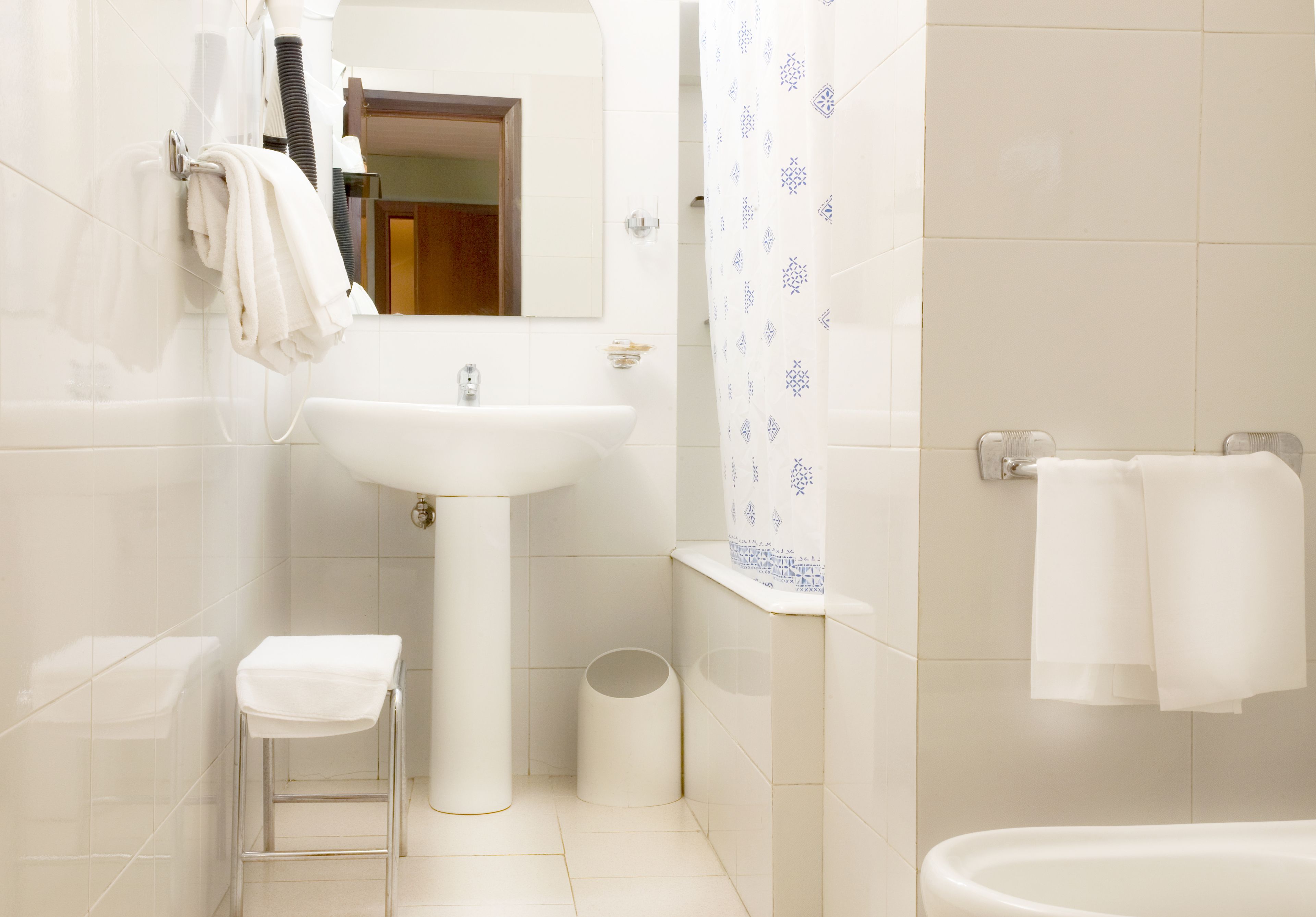 A bathroom with a sink, mirror, towel rack, and shower curtain.