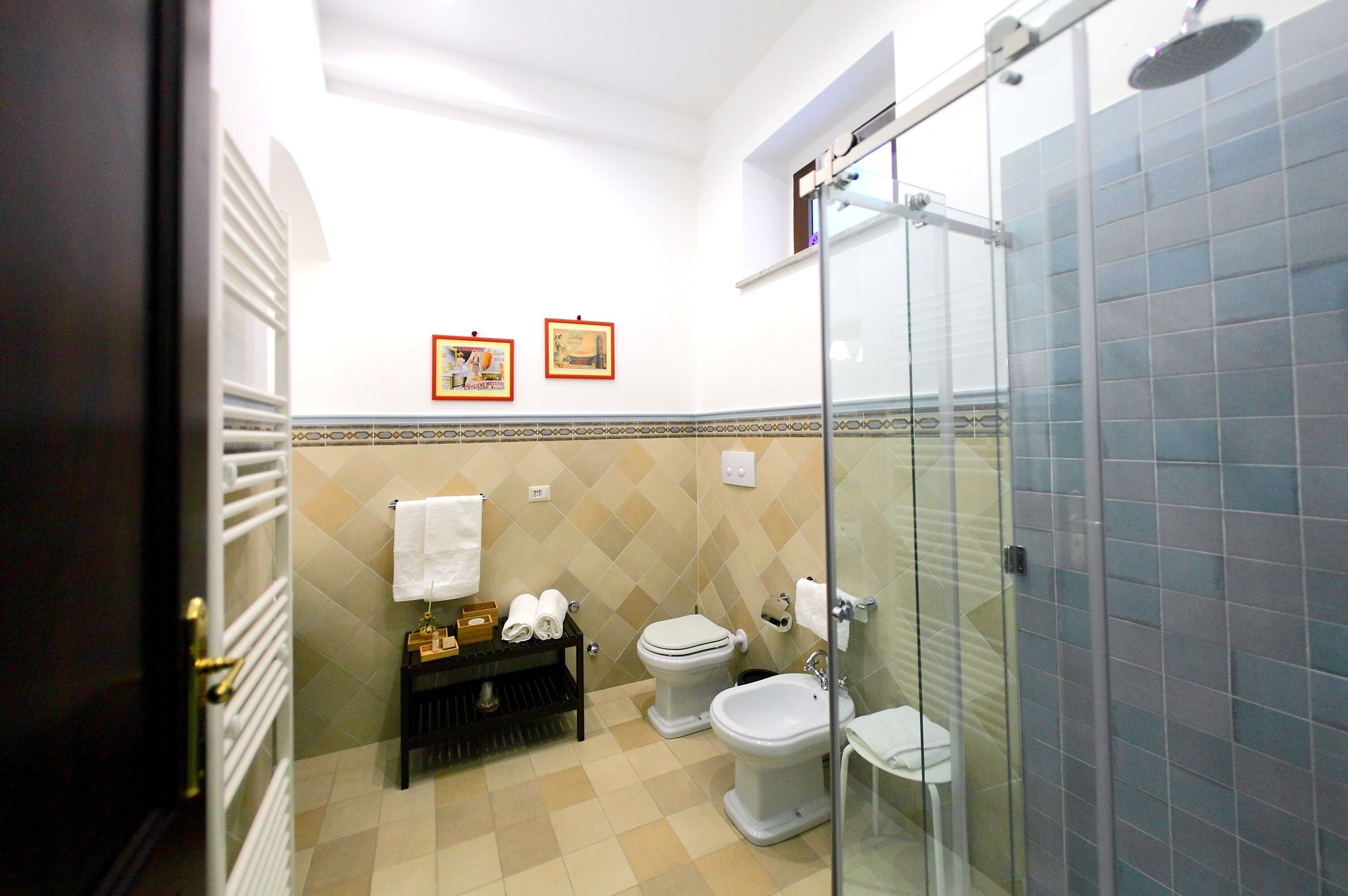 Ein Badezimmer mit Duschkabine, zwei Toiletten, einem Waschbecken und einem Handtuchhalter.