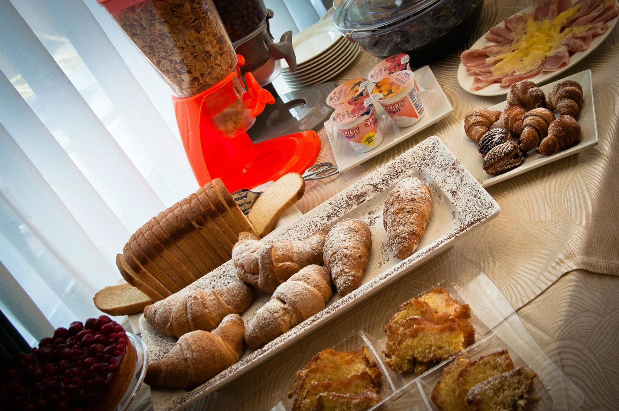 Una mesa de buffet con diversos alimentos, incluyendo pasteles, pan y postres.
