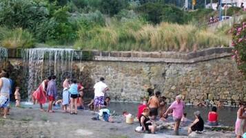 Un grupo de personas en un manantial termal natural con una pared de piedra y una cascada.