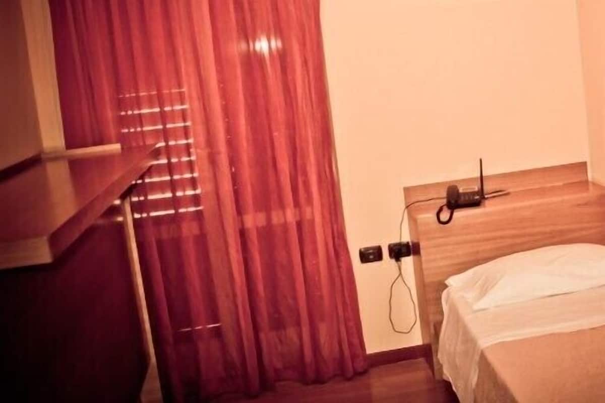 Una habitación de hotel pequeña y ordenada, con una cama individual, un escritorio y una silla.