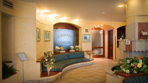 A hotel lobby with a curved seating area, a reception desk, and framed artwork on the walls.