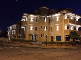 Un hotel de varios pisos con entrada central, balcones y fachada bien iluminada.
