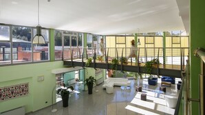 A spacious indoor area with a high ceiling, large windows, and a mezzanine level. - Sardegna Termale Hotel & SPA (Sardara)