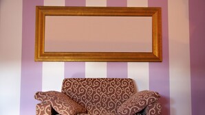 Una habitación con pared a rayas, un sofá marrón con diseño y un marco de madera.