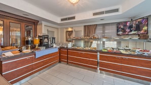 A modern hotel kitchen with a buffet, wooden cabinets, and a television. - Hotel Daphne - Special Class (Istanbul)