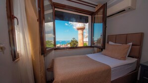 A bedroom with a bed, a window with curtains, and a view of a tower. - Hotel Daphne - Special Class (Istanbul)