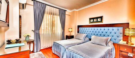 Une chambre d’hôtel avec deux lits, un bureau, une chaise, une table de chevet et une lampe.