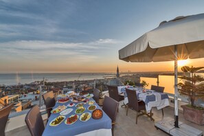 A rooftop dining area with a table set for a meal, overlooking a cityscape and the sea. - Hotel Daphne - Special Class (Istanbul)
