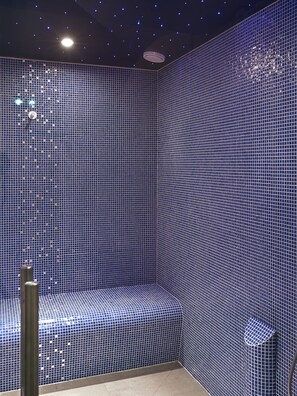 A room with a patterned blue tile wall, a curved bench, and a ceiling with small lights. - Monsieur Cadet Hôtel & Spa (Paris)