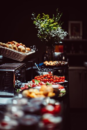 A buffet table with various food items and a decorative plant. - Monsieur Cadet Hôtel & Spa (Paris)