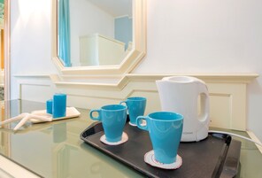 Una bandeja con tres tazas azules y una tetera blanca sobre una mesa de vidrio.