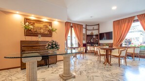 Un comedor con suelo de mármol, una mesa con cubierta de vidrio y sillas de madera.