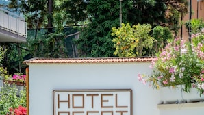 Un hotel con zona de piscina con baldosas, sillas de descanso y un mosaico que representa una escena costera.