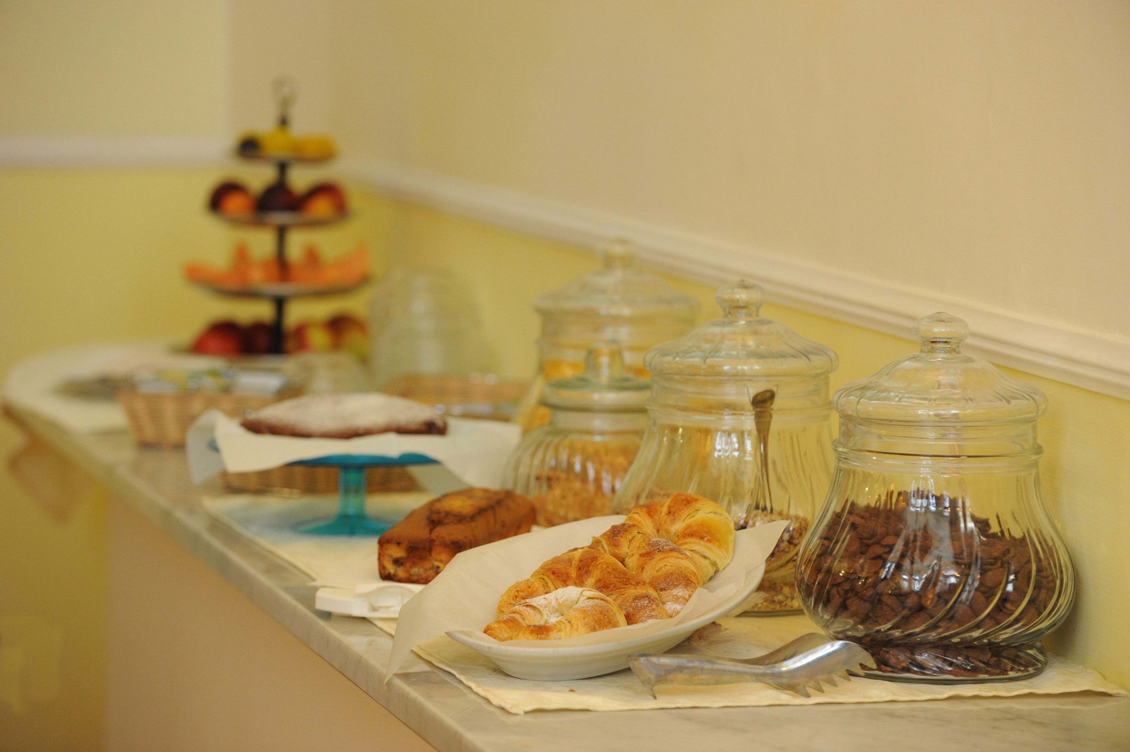 Ein reichhaltiges Buffet mit verschiedenen Speisen, darunter Gebäck, Sandwiches und Gläsern mit Aufstrichen.