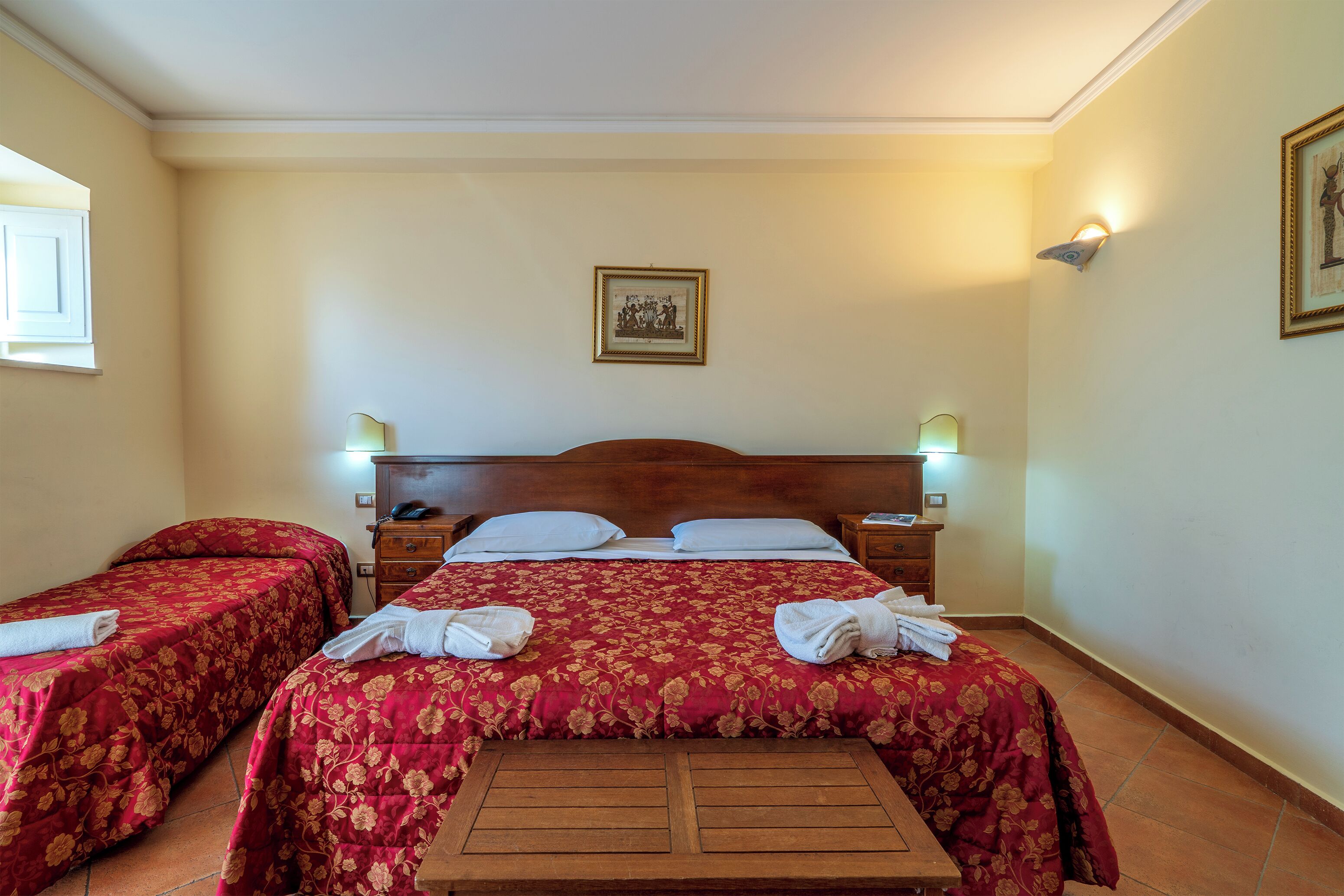 Ein Hotelzimmer mit zwei Einzelbetten, einem Holzkopfstück, Nachttischlampen und einem kleinen Tisch.