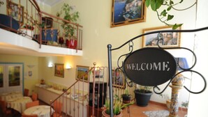 A cozy interior with a staircase, a 'WELCOME' sign, and potted plants. - Hotel Mediterraneo (Syracuse)