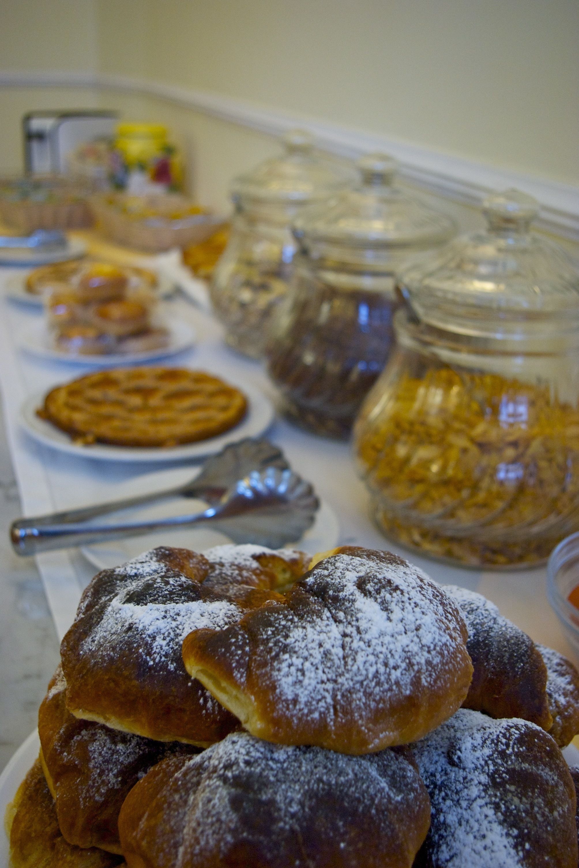 Une table de buffet proposant divers plats, notamment des pâtisseries et des pots de confitures.