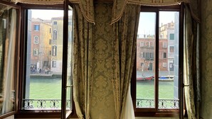 Ein Zimmer mit zwei Fenstern, jedes mit Blick auf einen Kanal und Gebäude.