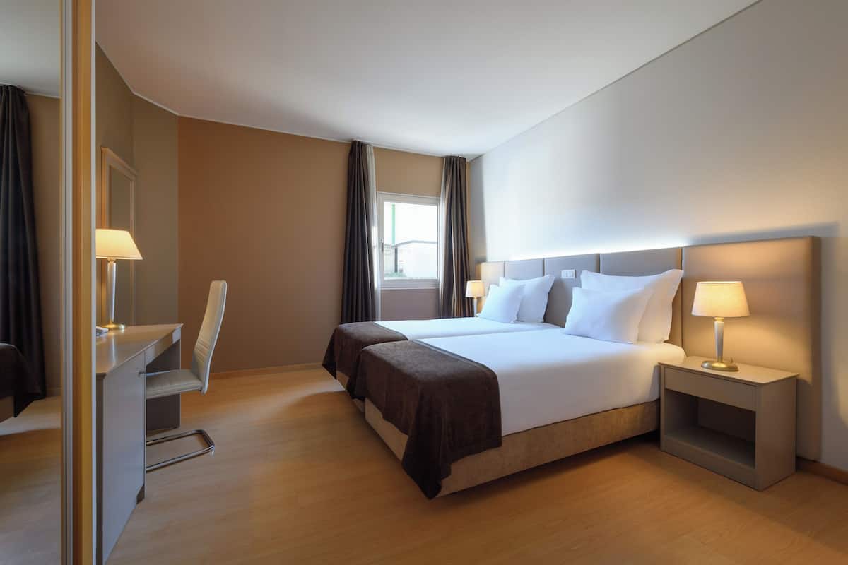 A hotel room with a large bed, bedside tables, a desk, and a chair.