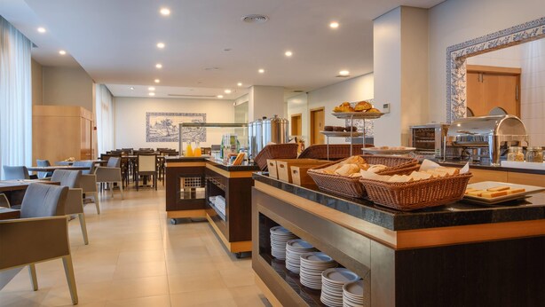 A modern breakfast area with a buffet setup, including bread baskets and a coffee station. - TRYP by Wyndham Porto Centro Hotel (Porto)