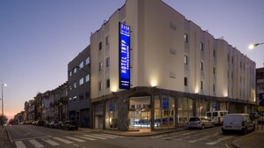 A hotel with a prominent sign, multiple floors, and a parking area. - TRYP by Wyndham Porto Centro Hotel (Porto)