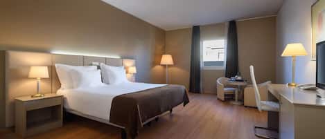 A hotel room with a bed, bedside tables, a desk, and a chair.