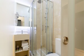 Un baño moderno con ducha de vidrio, lavamanos blanco y retrete.