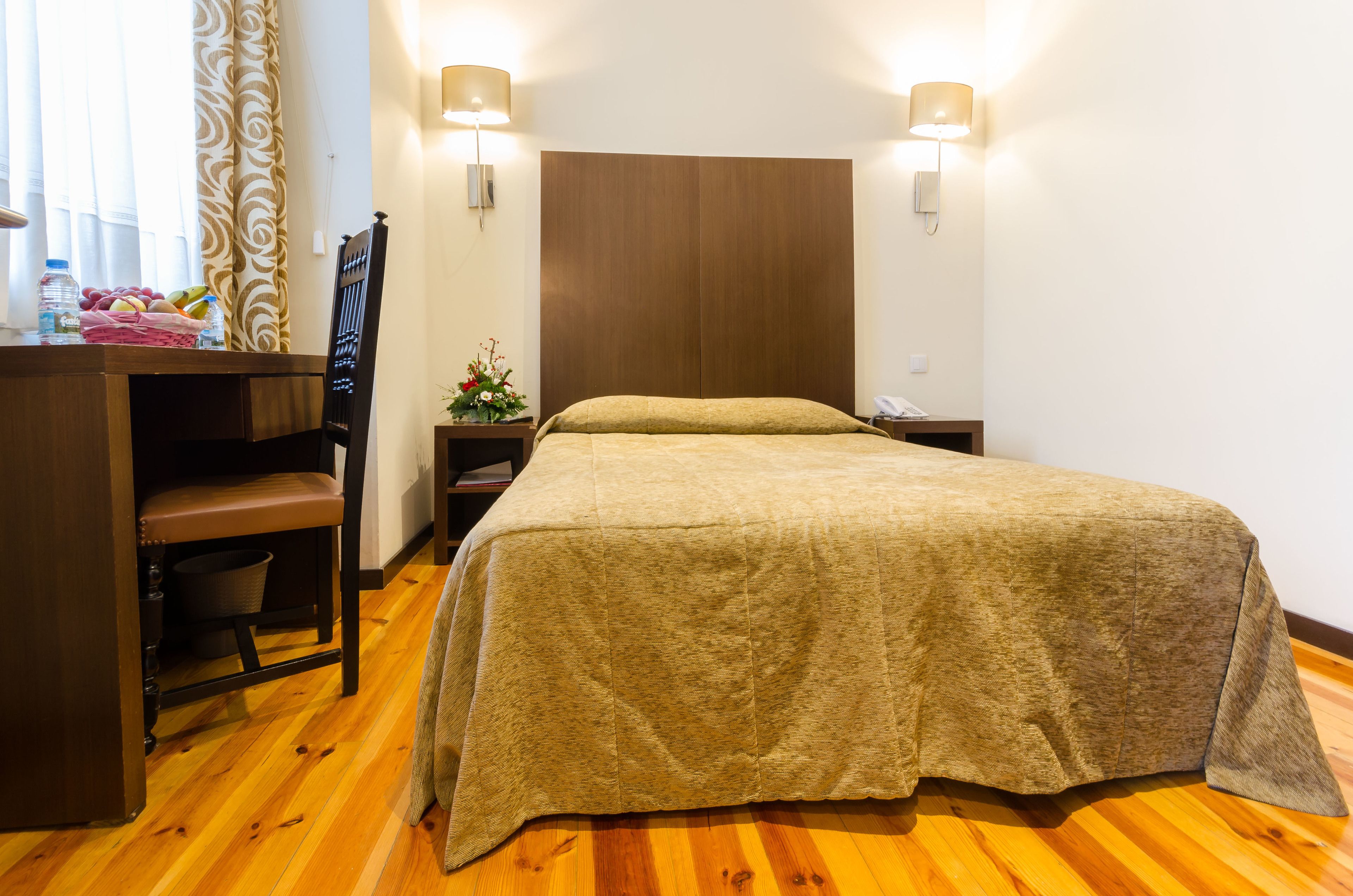 Une chambre à coucher avec un lit en bois, un bureau avec une chaise, une table de chevet et une lampe.