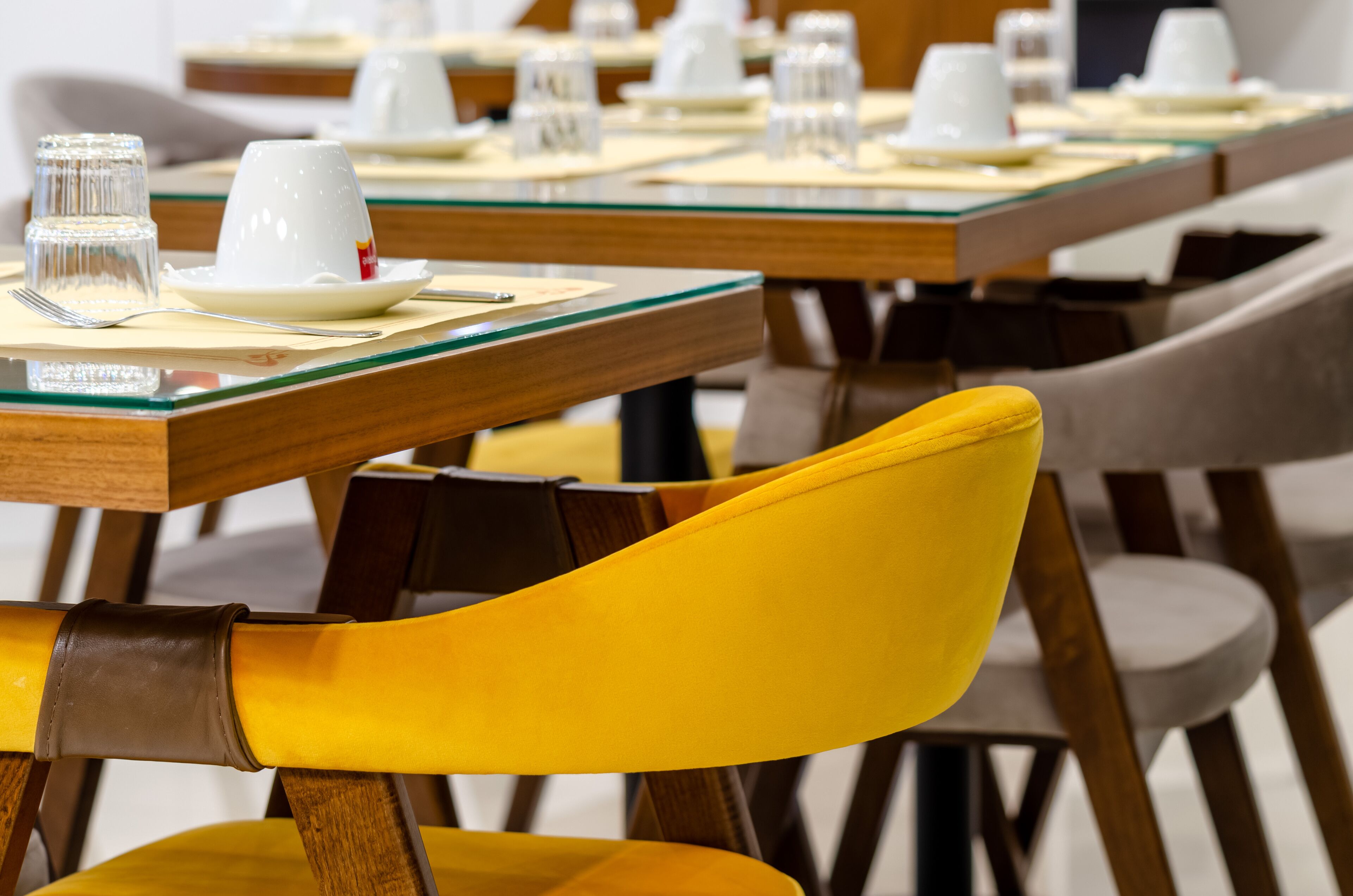 A dining area with multiple tables, each set with white plates, cups, and glasses.