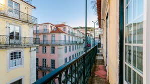Un estrecho callejón flanqueado por edificios, con balcones y una barandilla de metal verde.