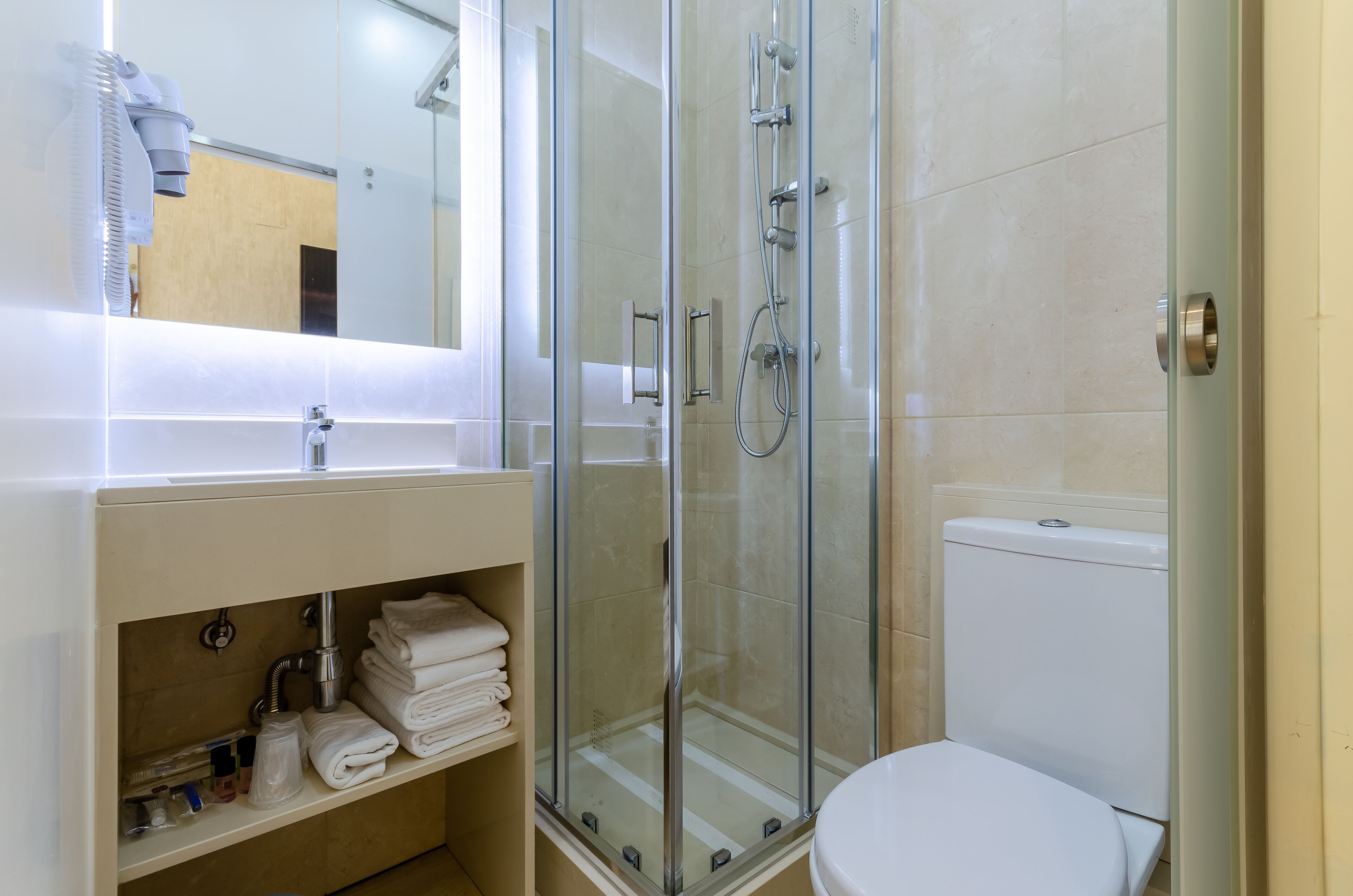 A bathroom with a glass-enclosed shower, a white sink, and a toilet.