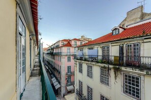 Un estrecho callejón entre edificios con balcones, algunos con plantas.