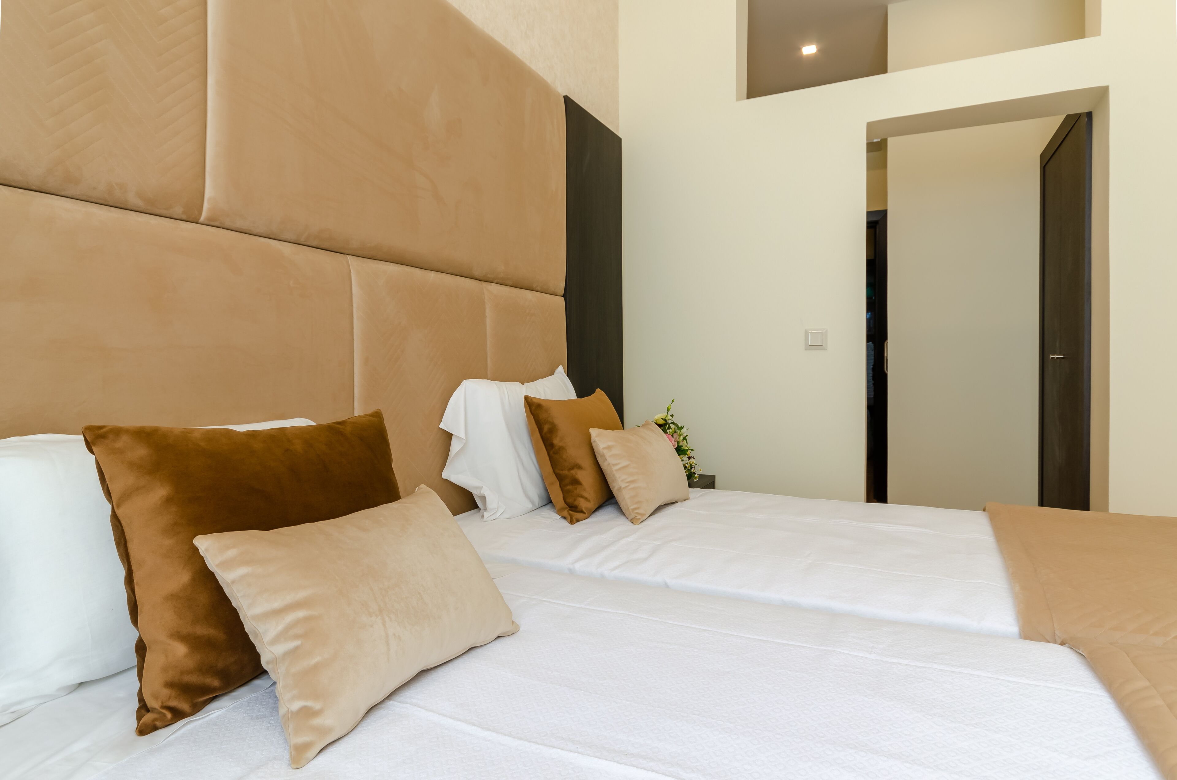 Una habitación de hotel moderna con una cama grande, varios almohadones y una mesita auxiliar.