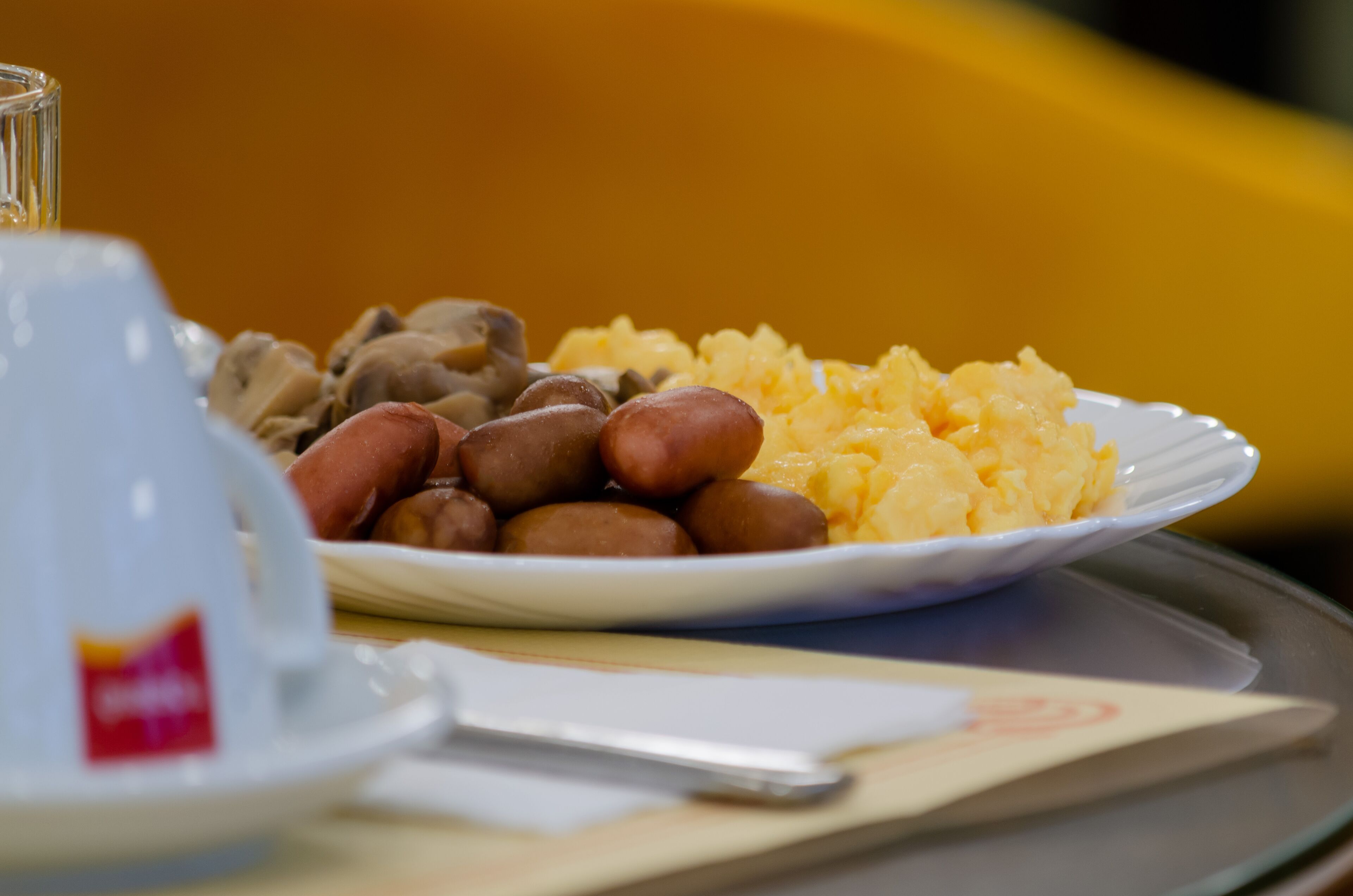 A plate with sausages and mashed potatoes on a tray.