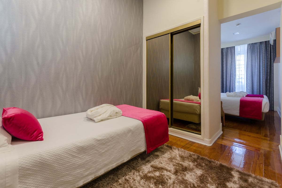 A hotel room with a bed, a mirror, and a sliding door.