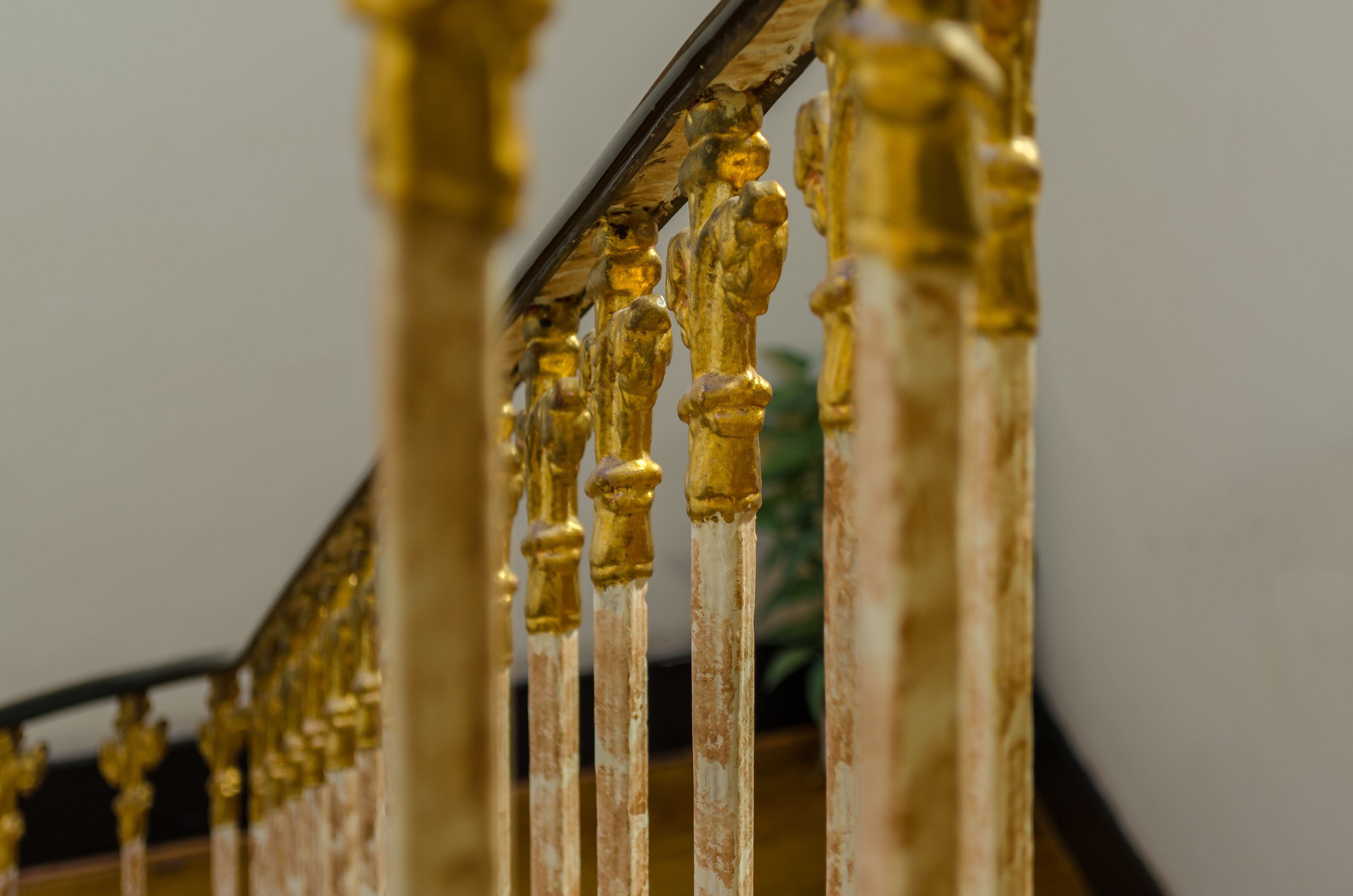 A close-up of a staircase with ornate golden balusters and a dark handrail.